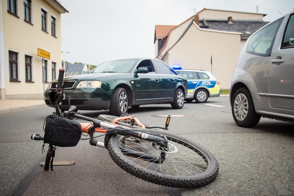 vélo couché au sol au milieu de la route et encerclé par des voitures