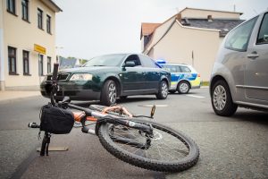vélo couché au sol au milieu de la route et encerclé par des voitures